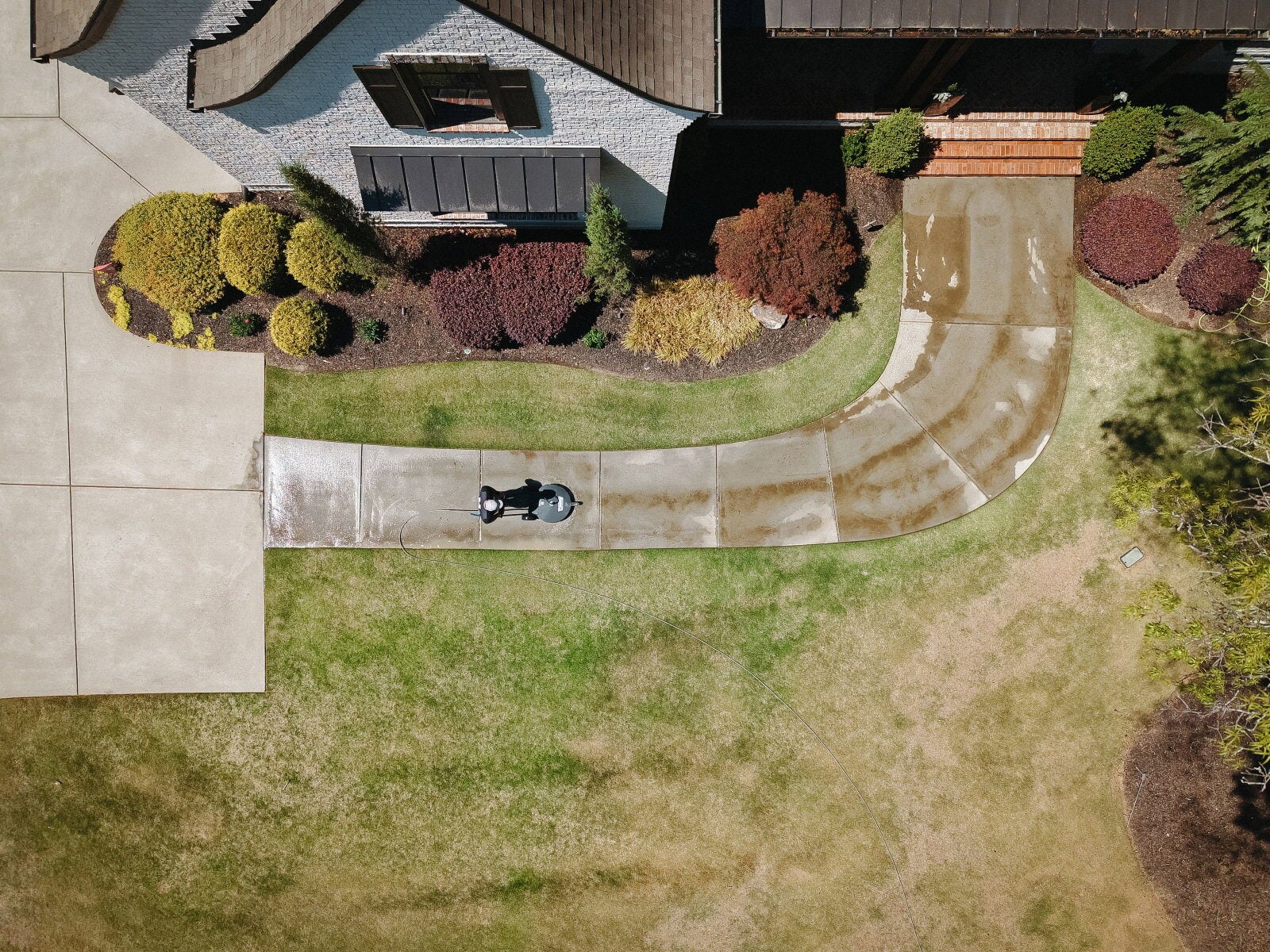 Aerial view of a walkway being surface-cleaned, half clean and half dirty