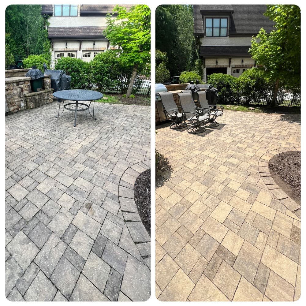 Patio area with stone pavers, outdoor furniture, and greenery in a residential backyard.